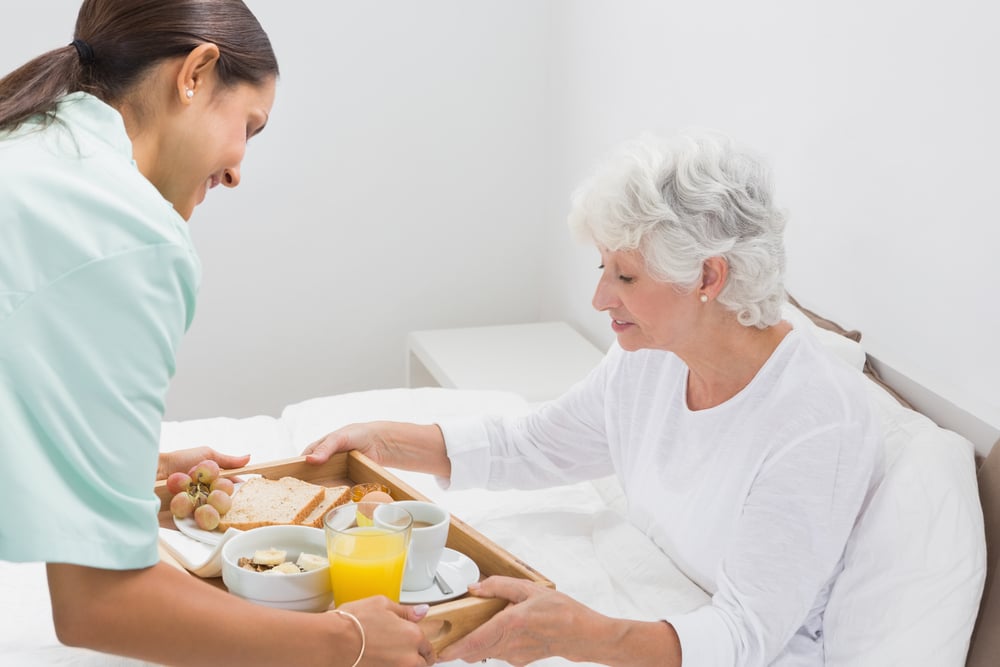 Elderly woman taking a breakfast with home nurse in the bedroom Elderly woman taking a breakfast with home nurse in the bedroom
